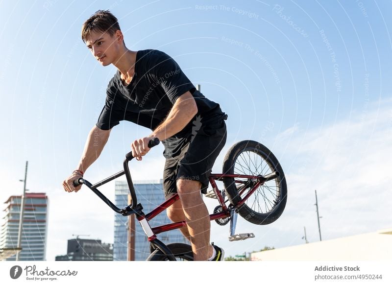 Man with BMX bike near on wall man bmx trick street urban sidewalk hobby male bicyclist casual activity vehicle bicycle motion daytime pavement practice balance