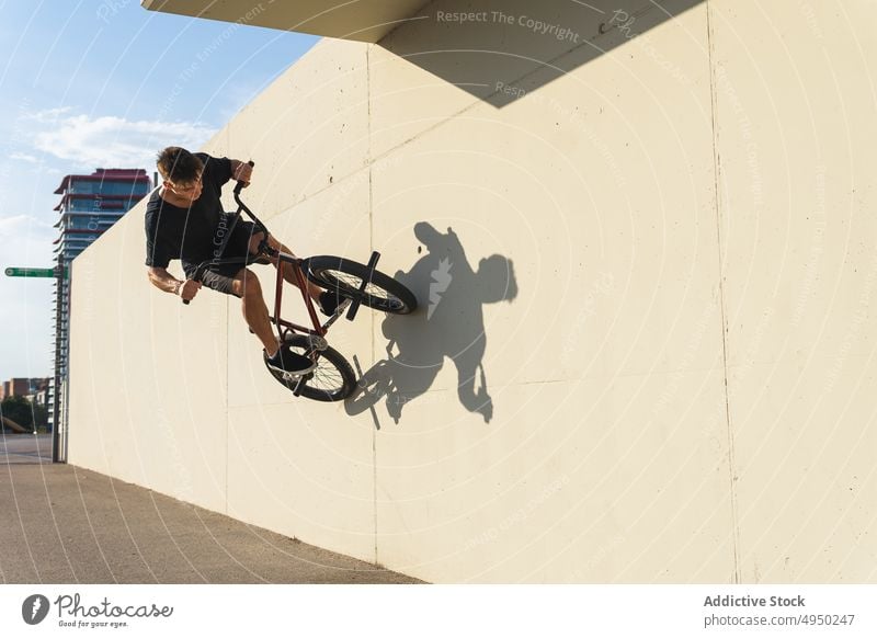 Young man doing wallride trick on BMX bike bmx skate park urban street male young stunt energy practice cyclist hobby activity transport focus recreation move