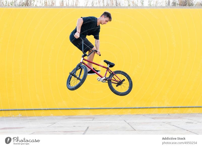 Man doing jump trick on BMX bike man bicycle bmx wall street weekend summer activity male energy urban stunt casual cyclist bicyclist contemporary practice move