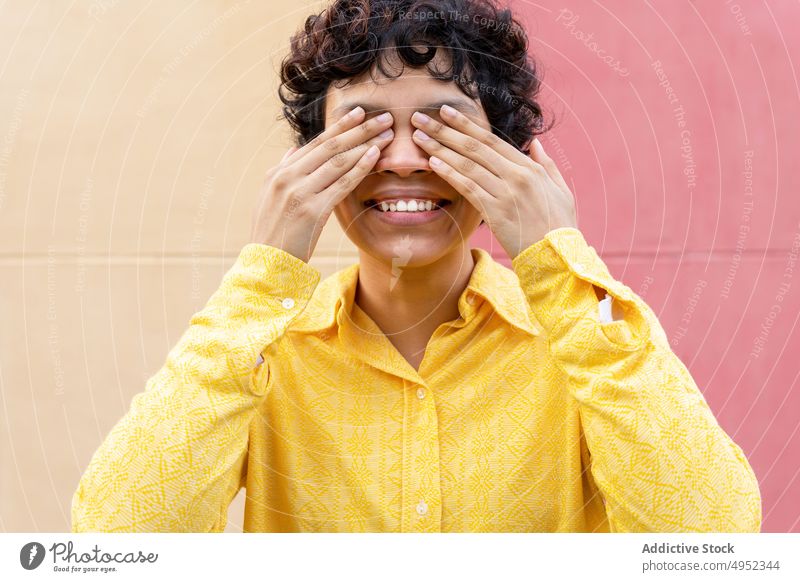 Happy ethnic woman covering eyes with palms close eyes closed cheerful surprise excited anticipate smile colorful bright vivid casual vibrant individuality glad