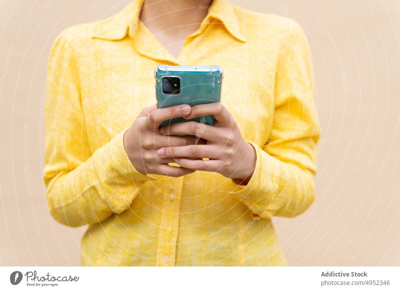 Content ethnic woman in bright shirt using smartphone urban colorful modern casual browsing communicate mobile app message texting gadget yellow curly hair