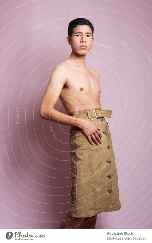 Feminine gay with naked torso on pink background model homosexual man feminine accept identity gentle touch thigh portrait skirt belt garment style lgbt