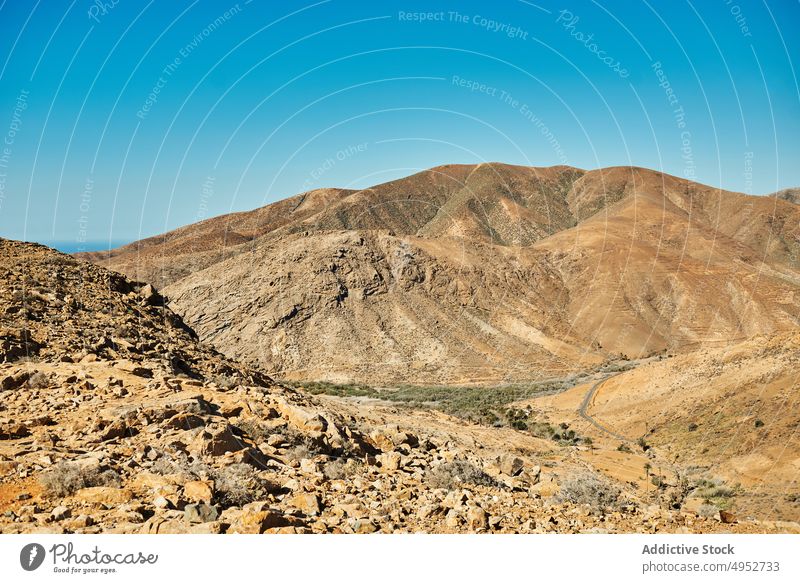 Wavy mountains under blue sky in sunlight nature highland landscape geology sandy atmosphere island wavy slope uneven dry barren terrain ridge air weather