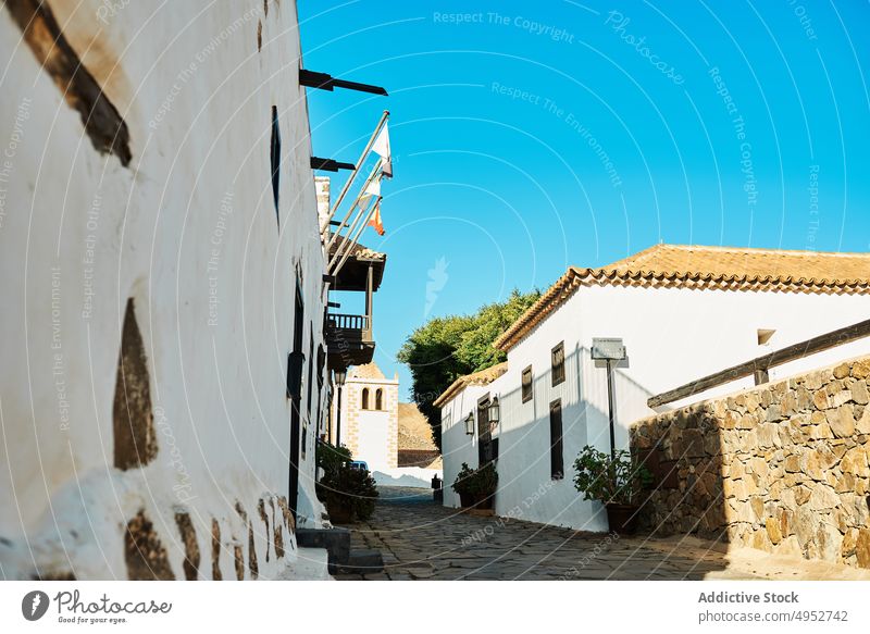 Cobblestone walkway between old dwelling houses under light sky street building architecture exterior route direction balcony neighborhood cobblestone rough