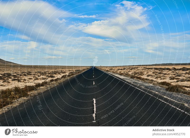 Empty asphalt road between desert with mount route direction nature landscape mountain blue sky cloudy empty marking line plant sandy atmosphere dry barren