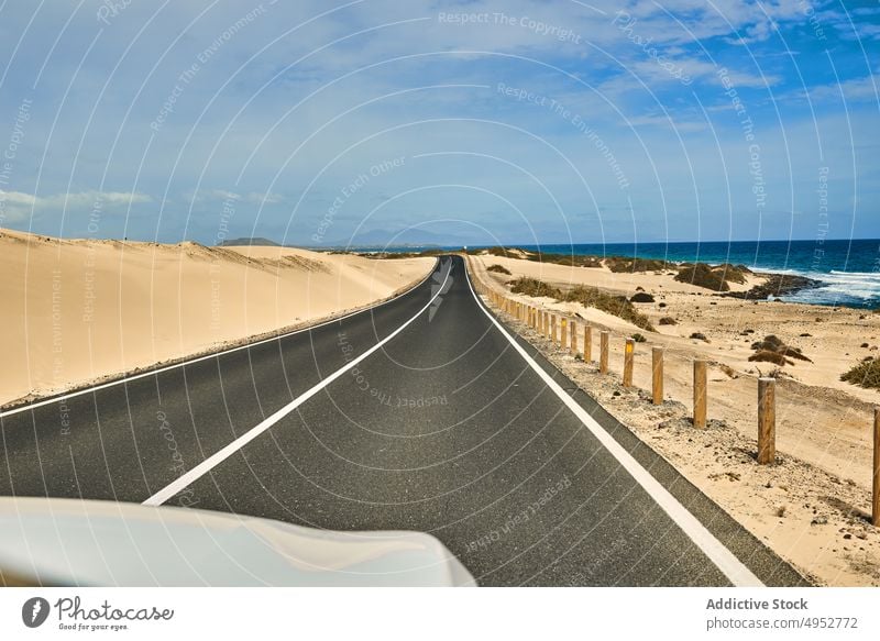 Road and ocean on Canary islands road canary islands fence coast water shoreline sand rocks fuerteventura landscape nature travel blue sky bank beautiful car