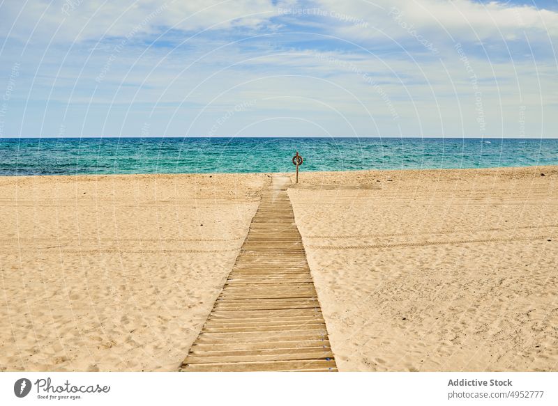 Lifesaver on post of sea shore under blue cloudy sky lifesaver footpath ocean blue sky nature seascape landscape horizon lifebuoy sandy beach boardwalk wooden