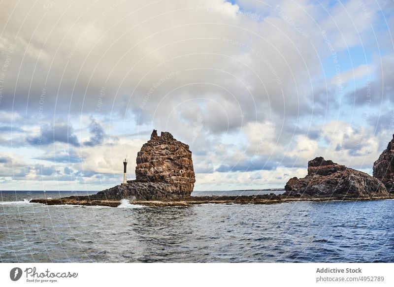 Rocky cliffs with lighthouse on seashore rock rough scenic seaside nature island picturesque peaceful canary spain marine stone stiff seawater tranquil coast