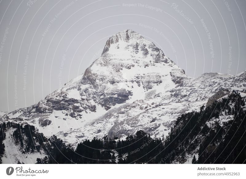 Mountain slope covered with snow under blue sky mountain steep rock tree highland stone nature cold wildlife peak environment winter season hillside pyrenees