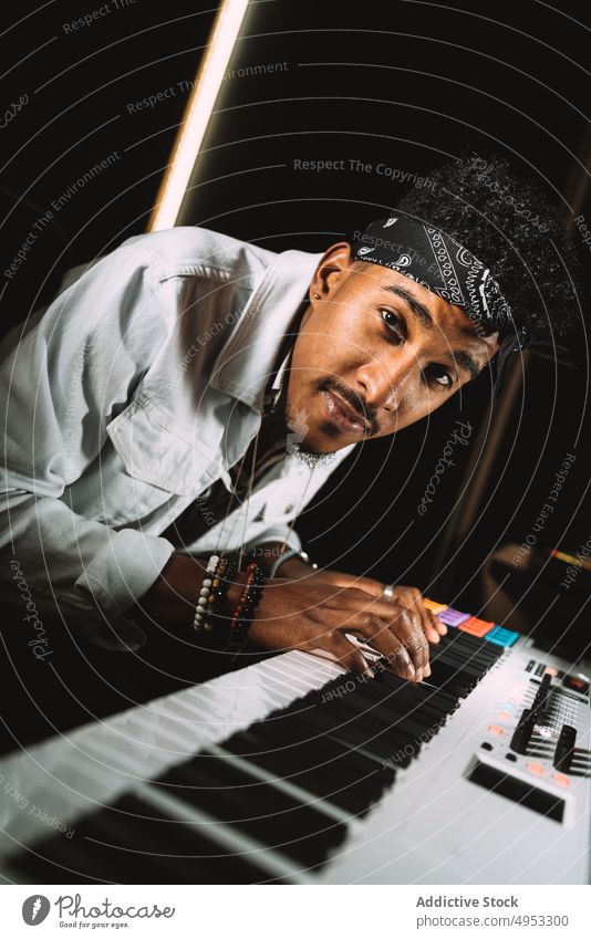 Black man playing synthesizer in studio musician audio hobby record skill acoustic male piano electric perform sound melody player tune instrument rehearsal