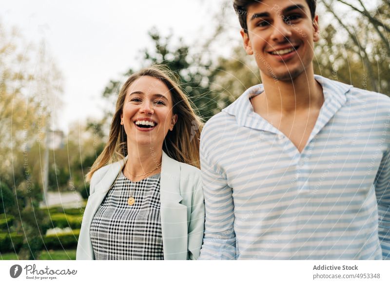 Smiling stylish couple holding hands walking in park in city happy love garden tender stroll relationship romantic cheerful together affection gentle smile