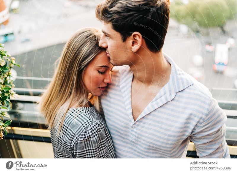 Young couple hugging in rooftop cafe in evening restaurant kiss date embrace romantic serene tender love together relationship affection bonding romance