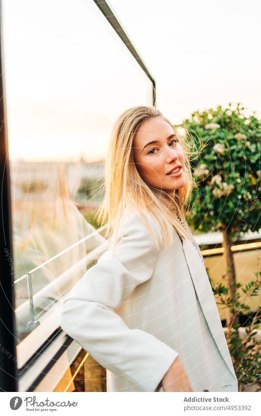 Dreamy woman standing in rooftop restaurant in evening dreamy cafe sunlight enjoy thoughtful female chill style relax glass window elegant sunset calm