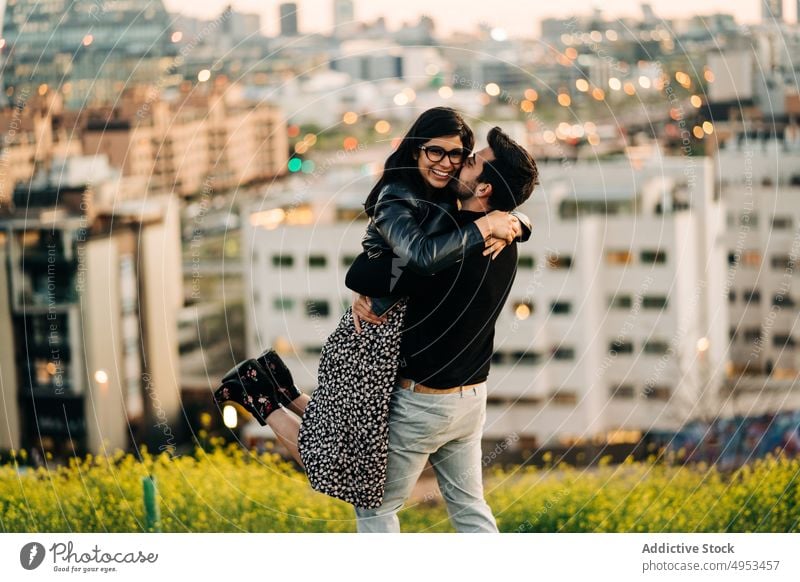 Ethnic man kissing happy girlfriend in city couple embrace raise portrait relationship amour romantic pleasure town love soulmate evening house fondness enjoy