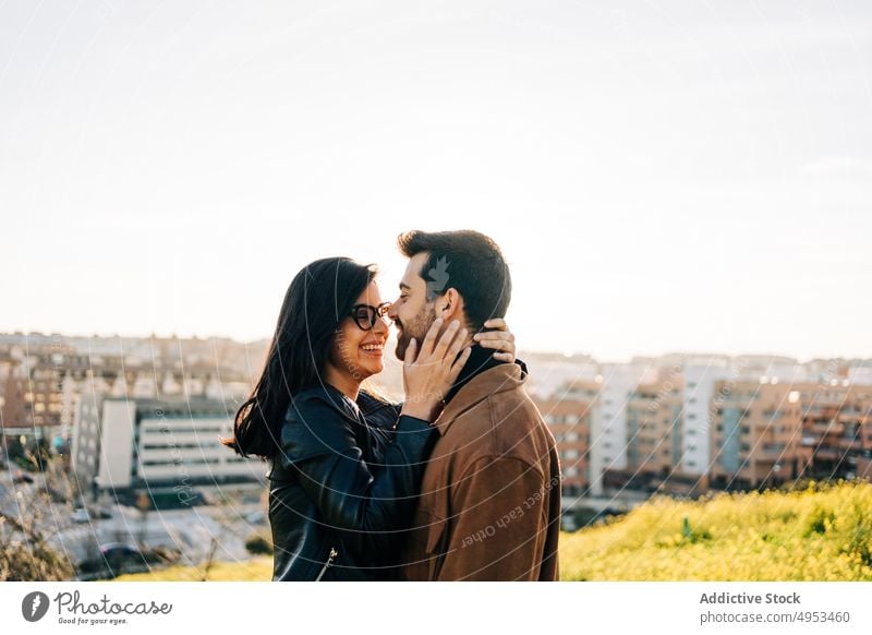 Smiling ethnic couple embracing against urban buildings embrace love relationship cheerful talk spend time soulmate city sky smile content speak glad candid