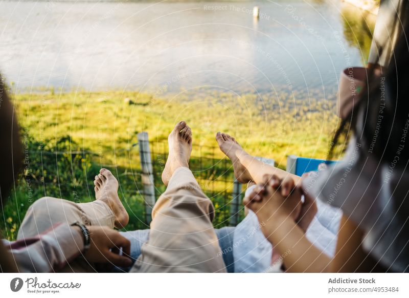 Crop traveling couple sitting on bed in van vacation traveler together caravan barefoot summer trip relationship girlfriend boyfriend carefree automobile parked