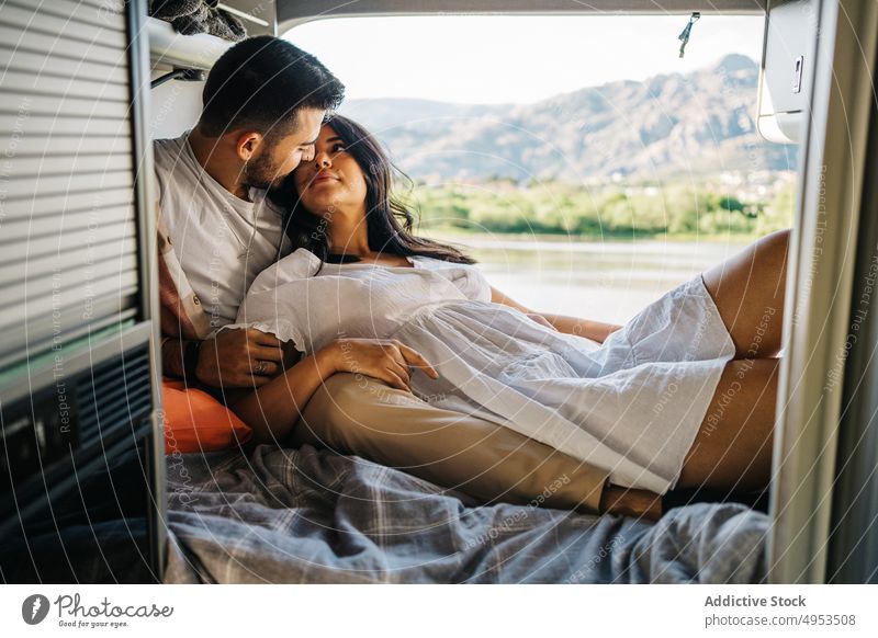 Loving ethnic couple of travelers lying in van bed caravan together camper tender hispanic love relationship girlfriend enjoy romantic trip boyfriend vacation