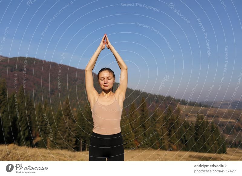 Young girl doing yoga fitness exercise outdoor in beautiful mountains landscape. Morning sunrise, Namaste Lotus pose. Meditation and Relax. Healthy Lifestyle.