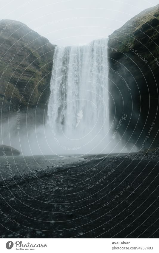 Dark landscape of the Skógafoss waterfall in Iceland during a moody day. Travel on van concept, road trip style. Visit Iceland and north countries concept.Copy space image