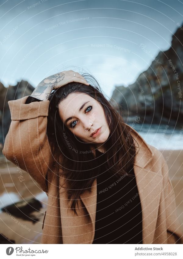 Stylish female on windy day near sea woman shore style young lifestyle leisure rest looking at camera relax coast trendy harmony calm tranquil serene peaceful