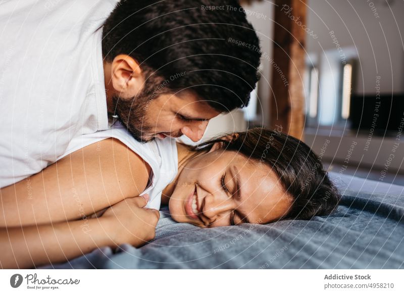 Calm young couple cuddling on comfortable bed in apartment tender affection relationship cuddle relax embrace love hug bedroom girlfriend boyfriend sit