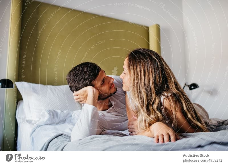 Calm young couple cuddling on comfortable bed in apartment tender affection relationship cuddle relax embrace love hug bedroom girlfriend boyfriend sit bonding