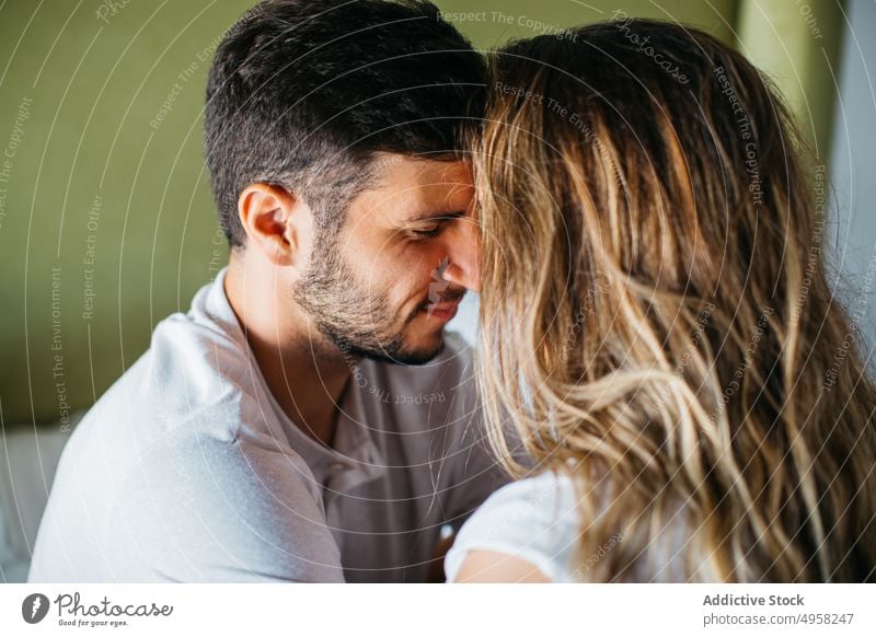 Calm young couple cuddling on comfortable bed in apartment tender affection relationship cuddle relax embrace love hug bedroom girlfriend boyfriend sit bonding