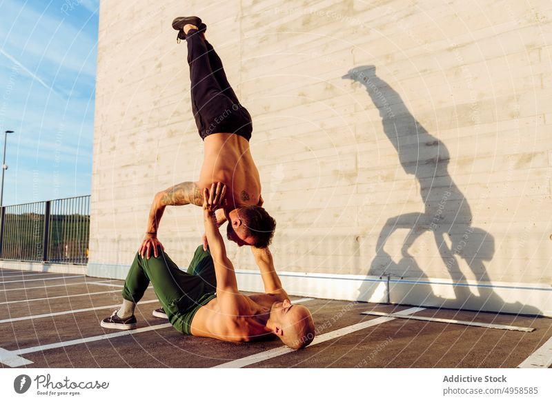 Young athletic men doing balance exercises together teamwork collaboration cooperation contact challenge steady commitment willpower togetherness fitness