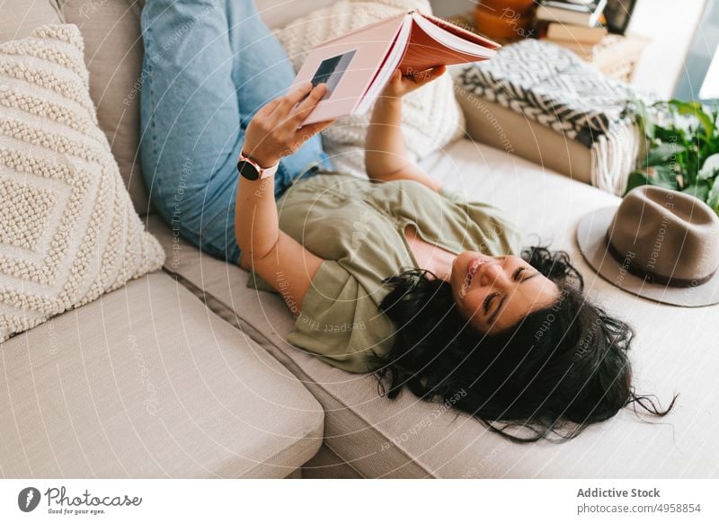 Woman reading a book at home female couch woman sofa lifestyle young leisure girl relax beautiful caucasian indoors adult literature room people attractive