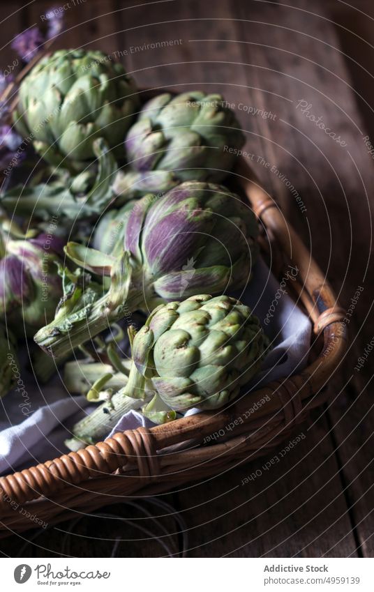 Green artichokes laid in basket green wicker bunch flower little purple fresh napkin decoration vegetable food healthy ripe vegetarian agriculture organic diet