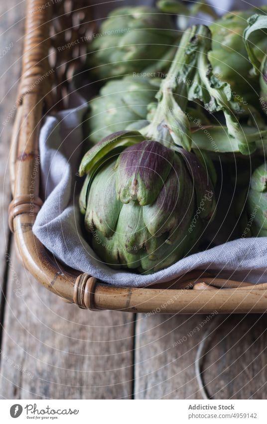 Green artichokes laid in basket green wicker bunch flower little purple fresh napkin decoration vegetable food healthy ripe vegetarian agriculture organic diet