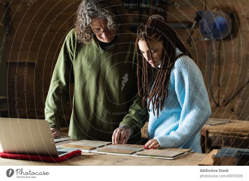 Woman choosing sample with carpenter in workshop woman artisan client choose order help joinery workbench female pick craftsman job industry manufacture busy