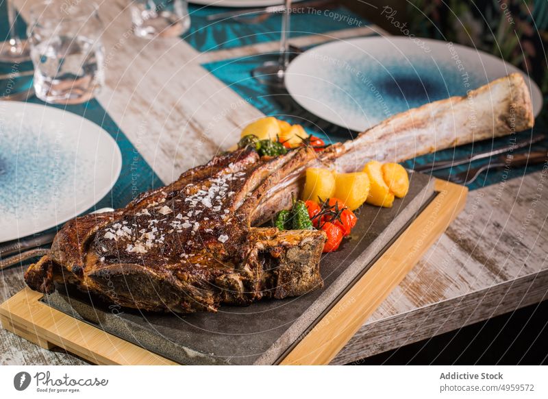 Delicious tomahawk steak with vegetables on cutting board menu food lunch dinner nutrition beef delicious gourmet bone salt grain seasoning tomato bright ribeye