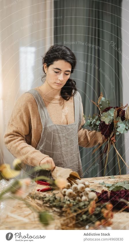 Calm pensive florist making amazing decorative bouquet with dry flowers in workplace compose woman home bunch creative plant composition floristry stem handmade