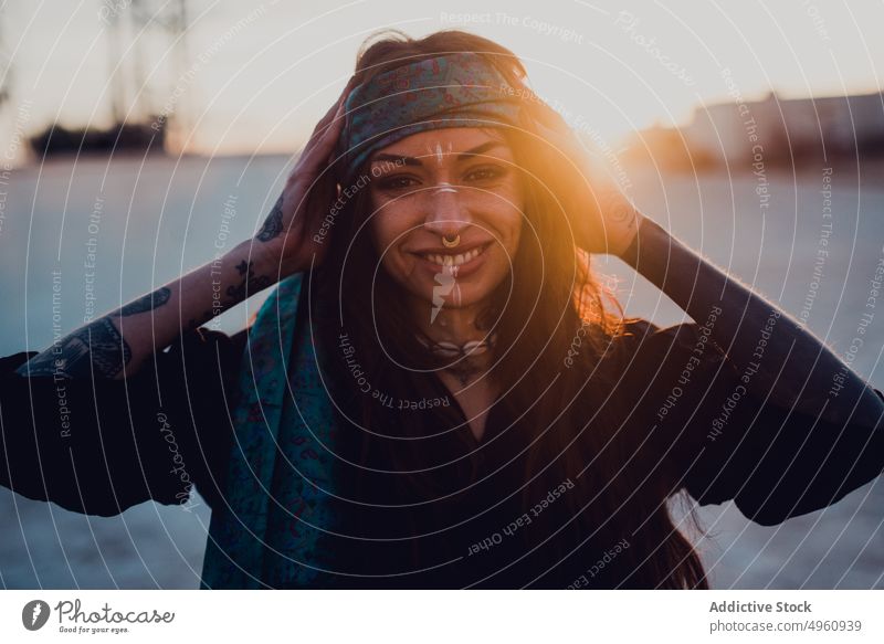 Happy young brunette with ritual white makeup and piercing on street woman headband tattoo happy hippie smile cheerful headgear sunset relax symbol joy face