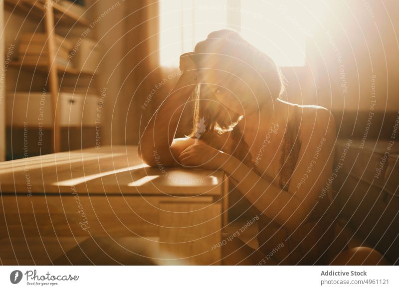 Serious woman leaning on table and looking at camera tattooed tranquil thoughtful sitting female adult thinking serious casual stylish lonely daydreaming