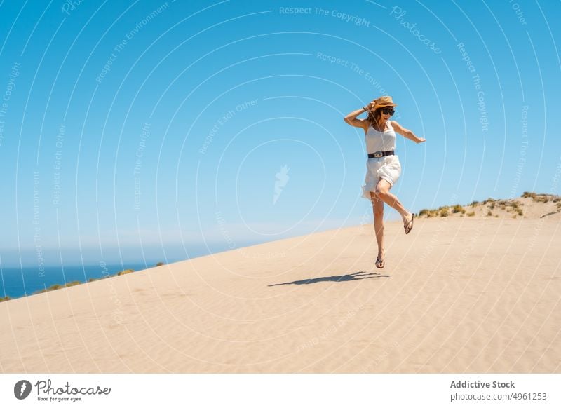 Smiling woman in dress walking on sandy beach in summer vacation seashore holiday enjoy sunhat female cabo de gata almeria jump cheerful spain dance smile