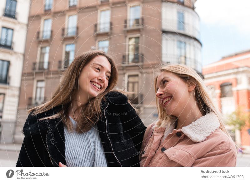 Optimistic women walking in city along street friend laugh having fun weekend together style trendy female madrid spain cheerful urban positive joy modern