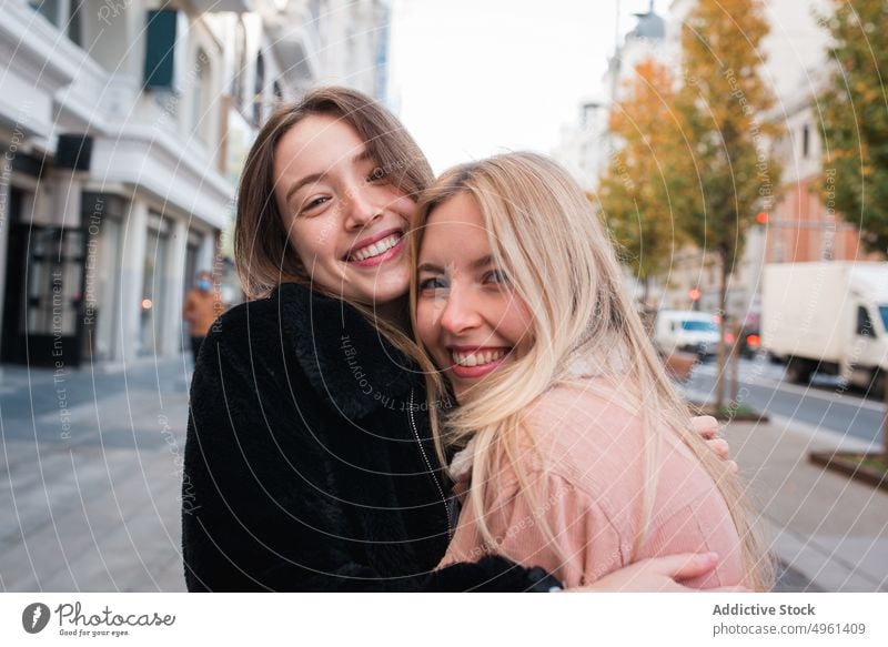 Smiling female friends looking at camera in city women best friend charming smile positive street stroll weekend madrid spain young happy cheerful joy trendy