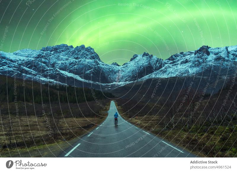 Traveler standing on road under sky with aurora traveler aurora borealis polar light mountain winter northern night norway lofoten islands snow nature