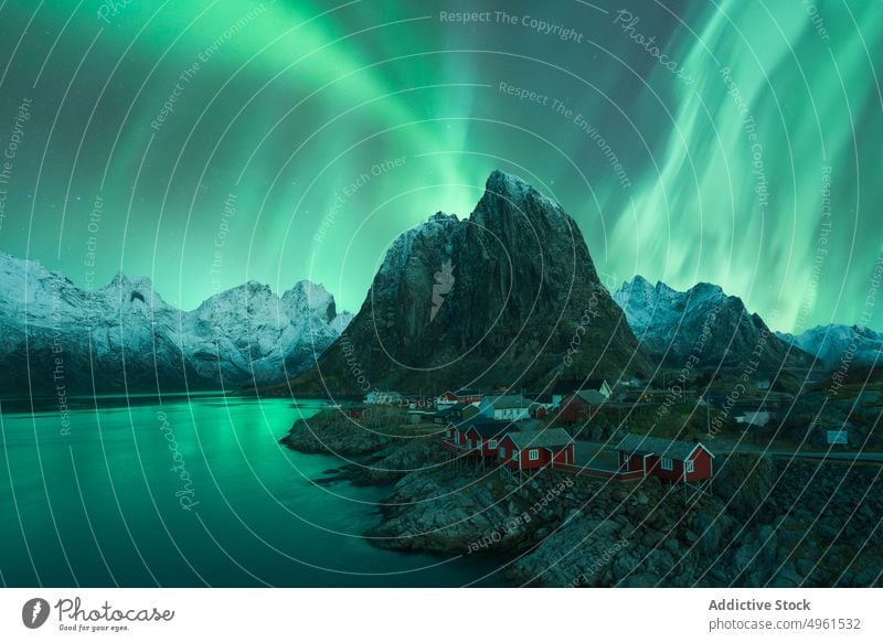 Northern lights above mountainous village near lake aurora borealis northern green highland sky house night lofoten islands norway illuminate glow breathtaking