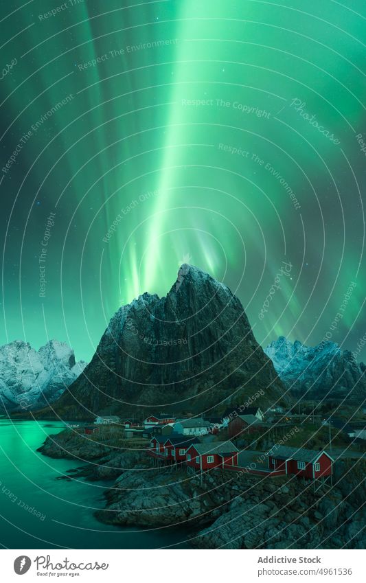 Northern lights above mountainous village near lake aurora borealis northern green highland sky house night lofoten islands norway illuminate glow breathtaking