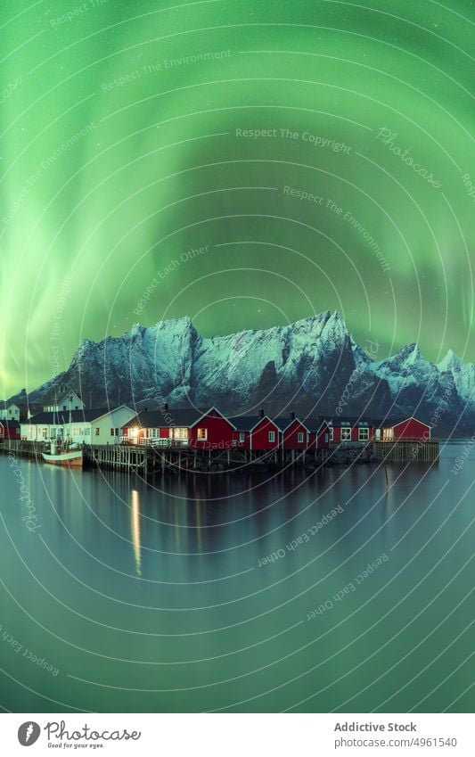 Northern lights above mountainous village near lake aurora borealis northern green highland sky house night lofoten islands norway illuminate glow breathtaking