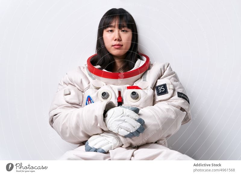 Asian cosmonaut looking at camera in studio woman break mission spacesuit wall lean portrait female young asian ethnic chinese japanese astronaut appearance