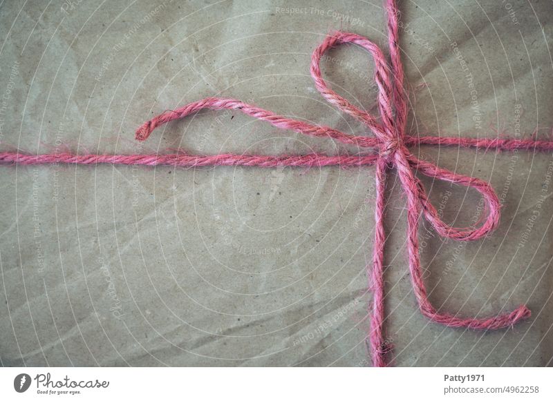 Gift wrapped with recycled paper and pink string. Close up of front with bow and text free space String Wrapping paper Bow Christmas eco Copy Space Birthday