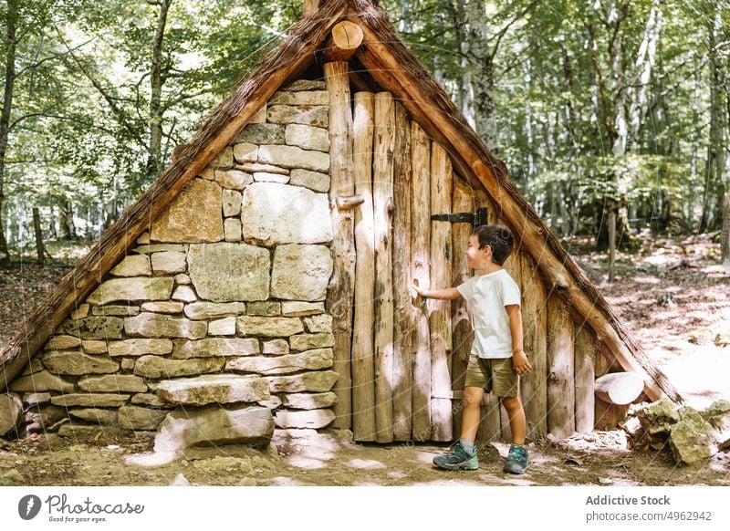 Boy opening door of hut boy forest weekend summer daytime explore countryside child a frame building entrance timber lumber sunlight woods daylight childhood