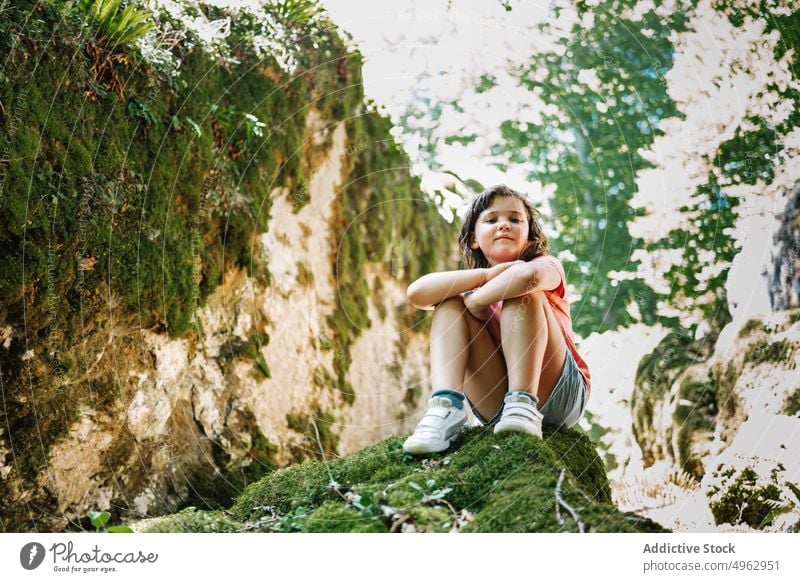 Girl sitting on stone in nature girl countryside summer weekend moss daytime admire season sunny kid arms crossed rock child rough trip casual boulder weather