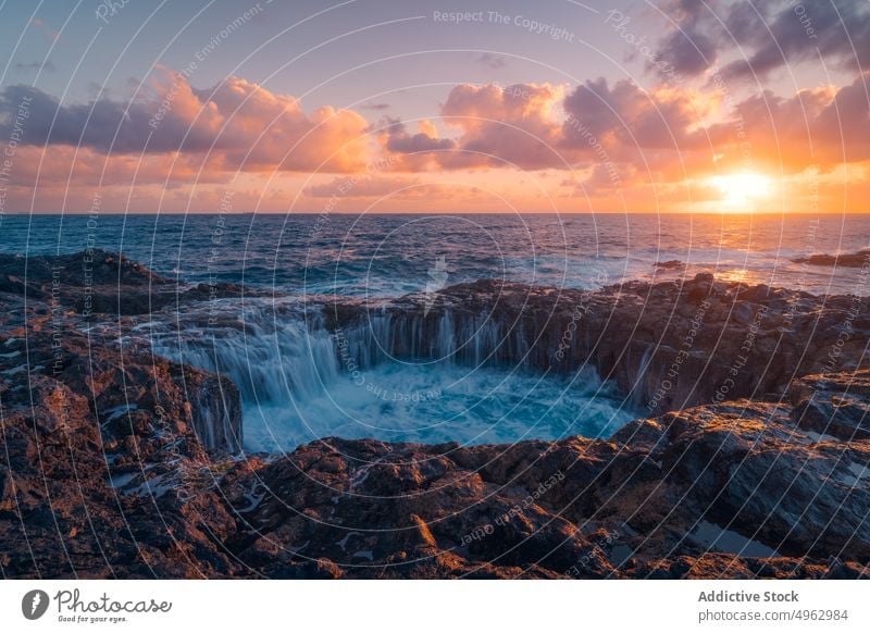 Scenery of waterfall under sunset sky cliff rocky seaside landscape power stream scenic environment gran canaria canary islands formation picturesque