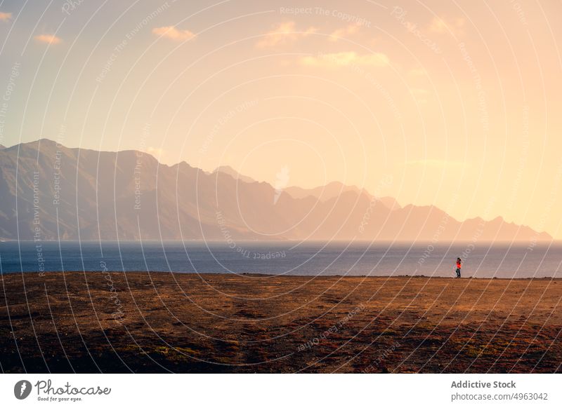 Anonymous traveler walking along seashore in mountains woman sunset coast highland rocky explorer gran canaria canary islands stroll nature sky beach scenic