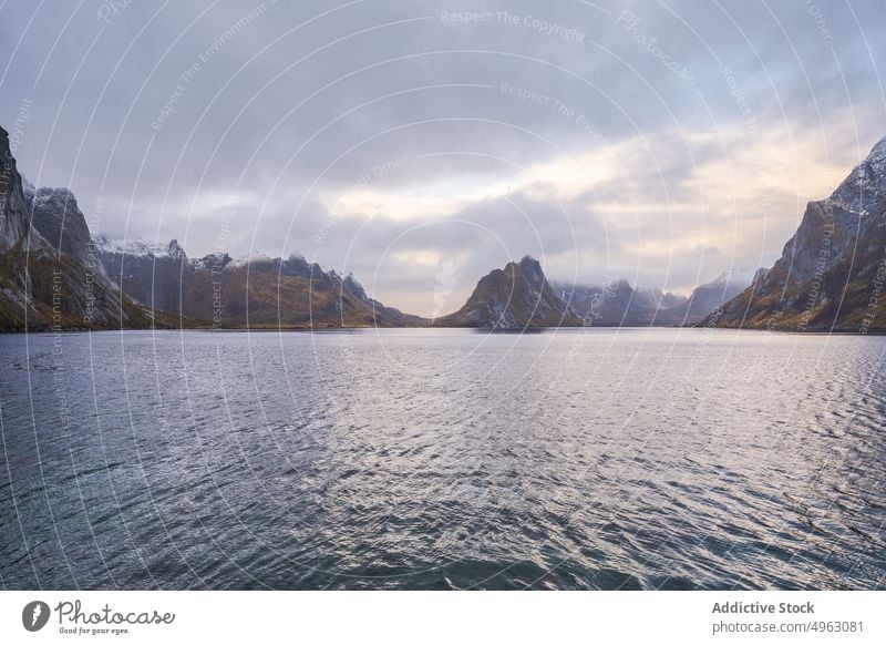 Rocky mountain ridge and wavy sea against gloomy sky in Norway landscape nature cliff snow highland range overcast cloudy massive peak rocky fjord geology reine